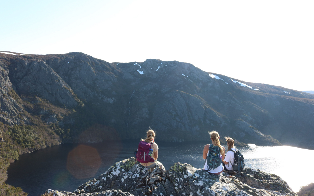 Students sitting on a cliff overlooking a lake 
