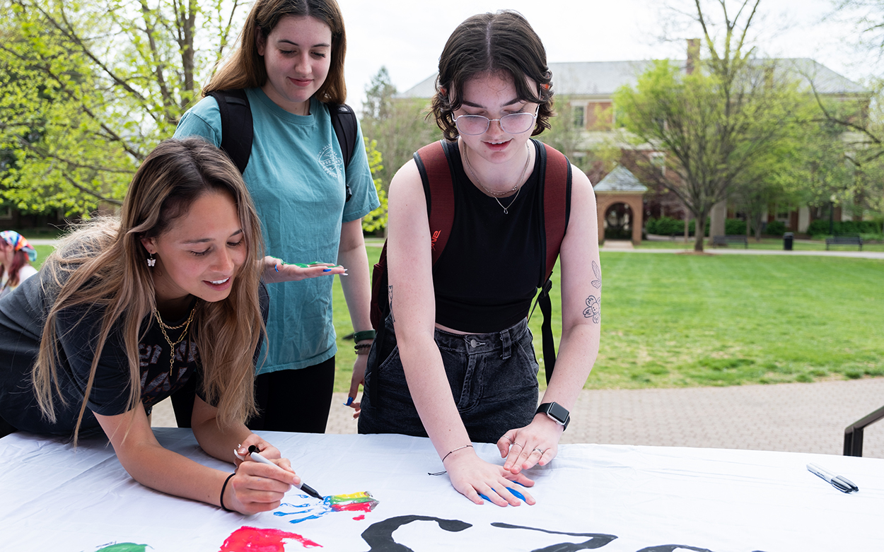 Students adding handprints to a banner