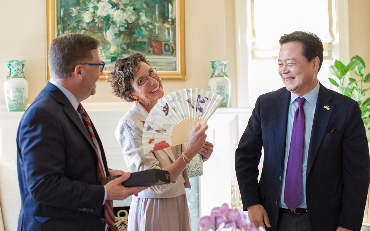 President Shushok and Ambassador Cho stand with Kelly Shushok who is holding a Korean fan