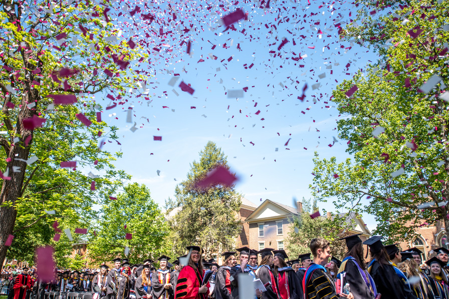 Students at graduation with confetti in the air.