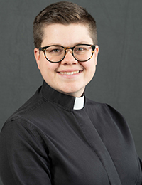 Young woman in black pastor's shirt with white collar smiles for a professional head shot