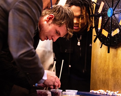 A student holding chopsticks leans in closely while taking part in one of the challenges organized at the Lunar New Year celebration