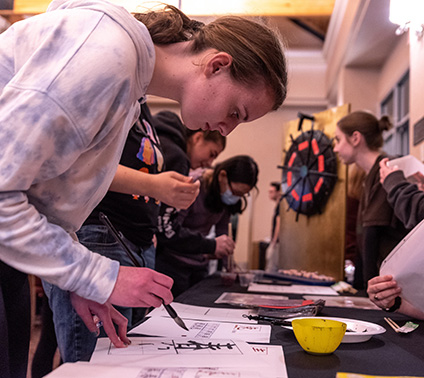 A student wields a paintbrush while trying to recreate a calligraphy sample