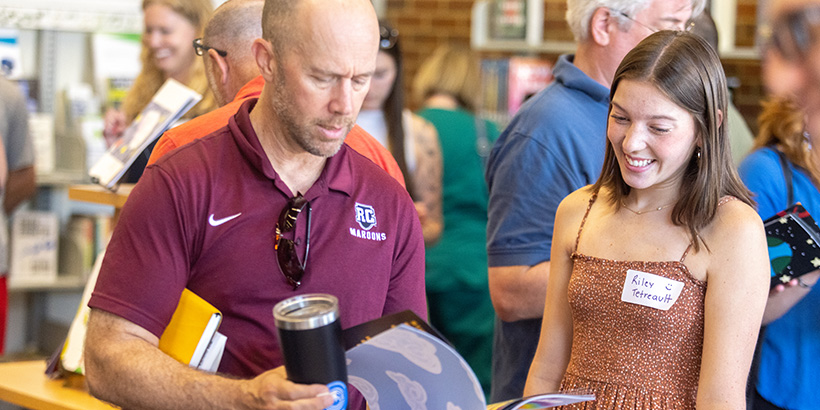 A student smiles while explaining her book to a guest at the project's unveiling