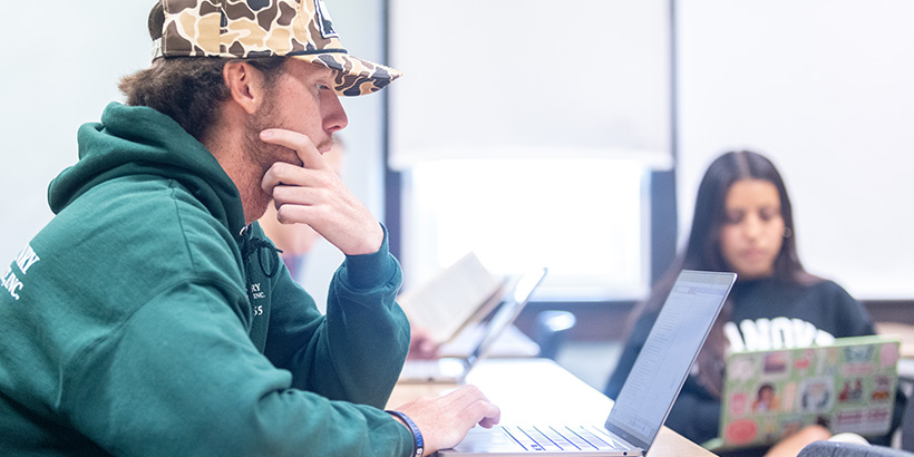 A student puts his hand to his chin while reading through constitutional research during class