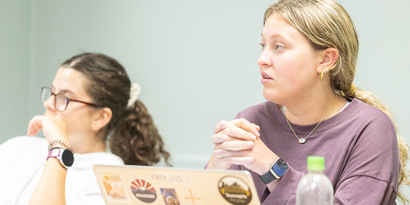 A student clasps her hands together while listening to a classroom debate