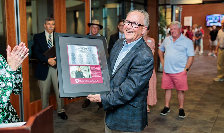 Athletic Director Scott Allison shows off a plaque that was presented to him during a retirement celebration on Alumni Weekend 2023.