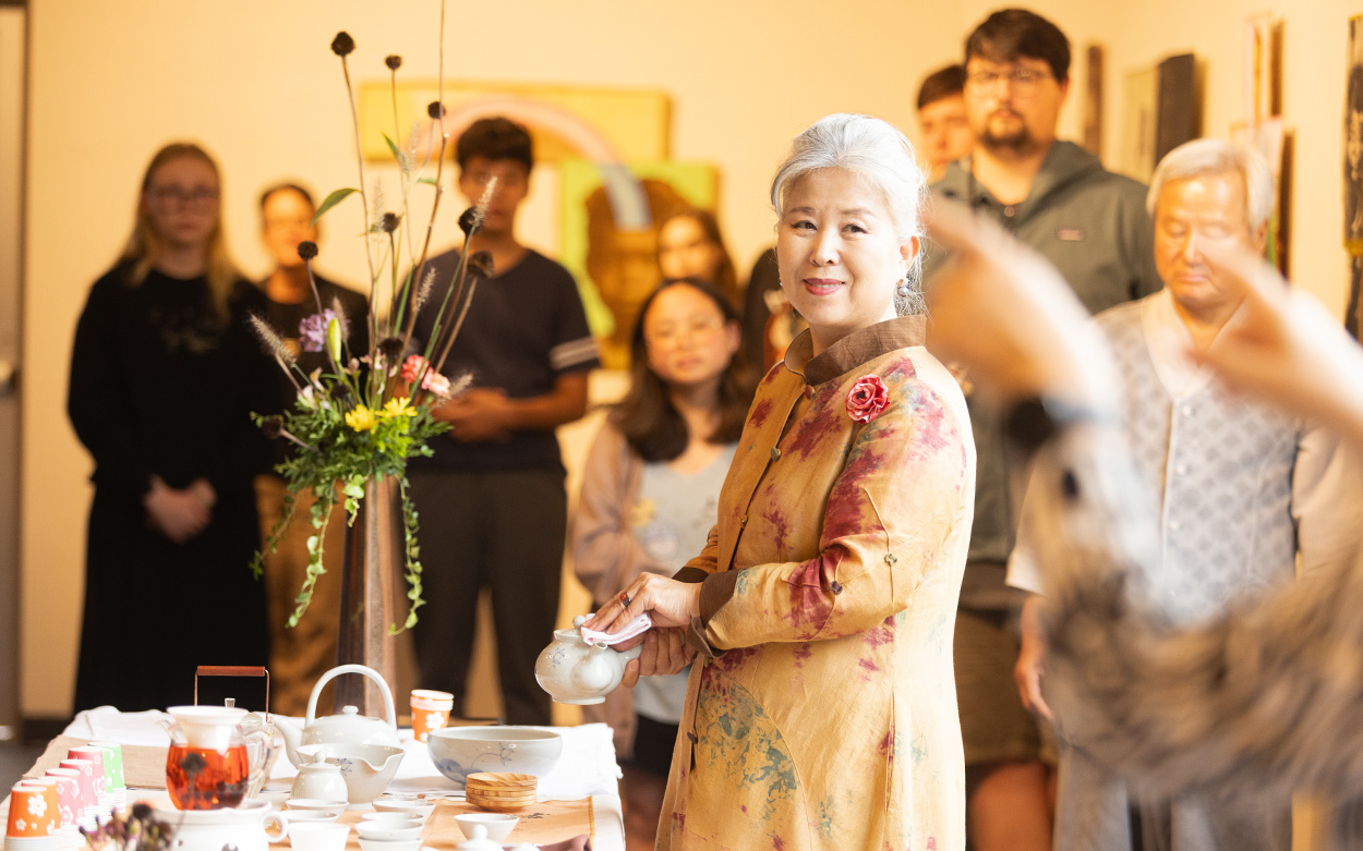 Woman smiling while standing with a table of tea after offering a speech on Korean traditions.