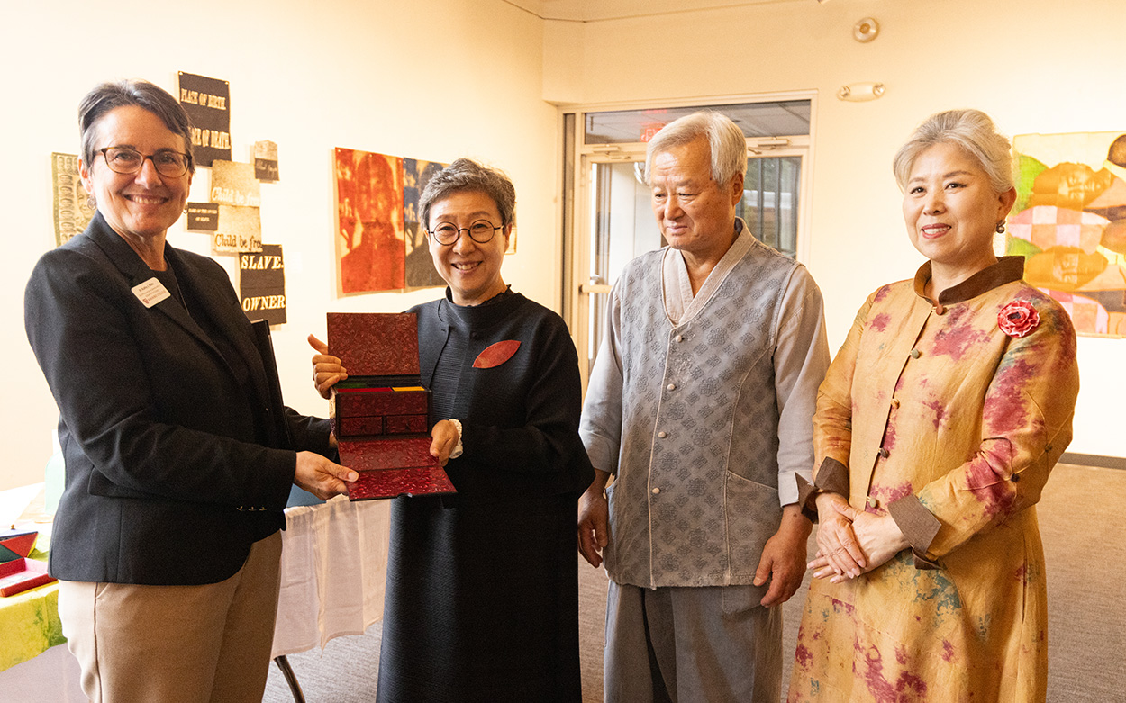 Dean of the College stands with 2 women and a man from the Hanji art and tea masters program.