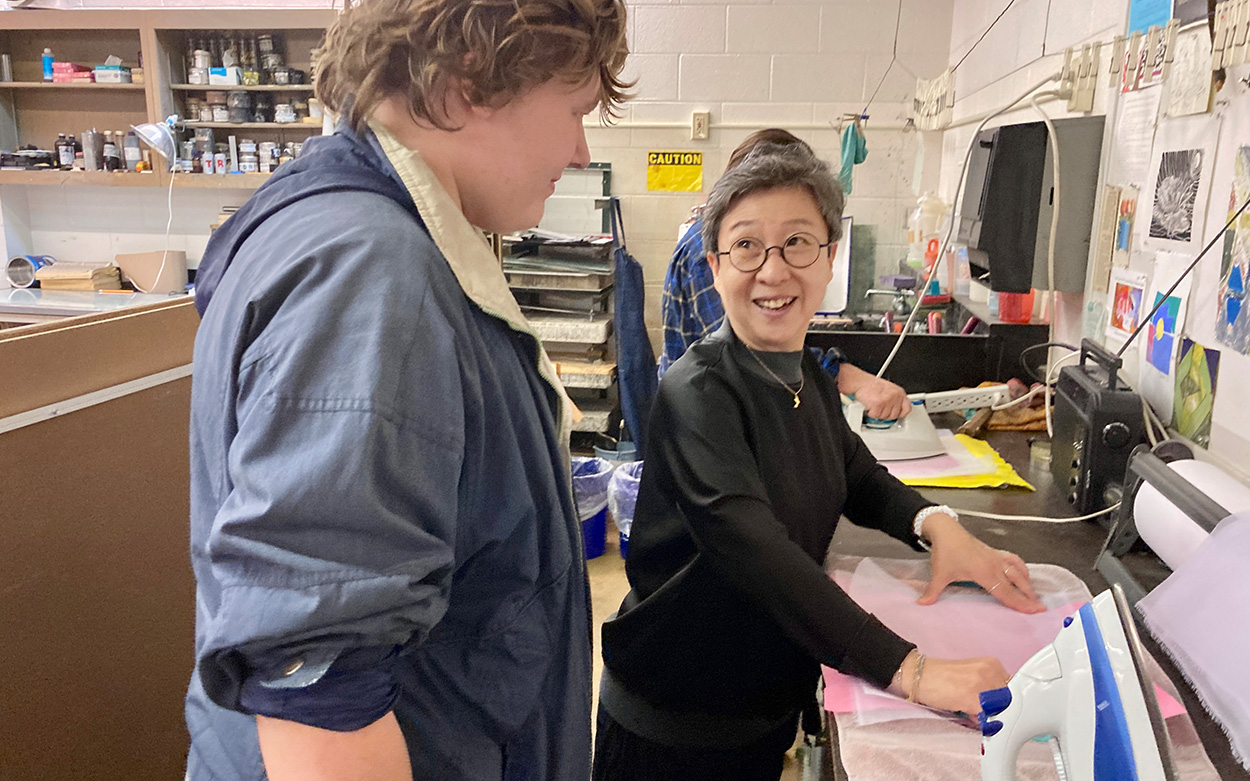 Woman teaching a student how to dry the paper.