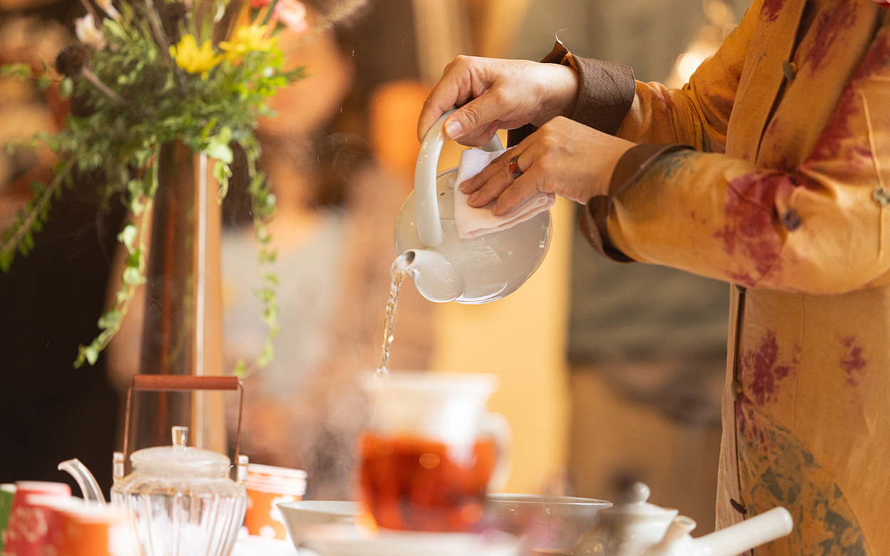 Woman pouring hot water from a tea pot.