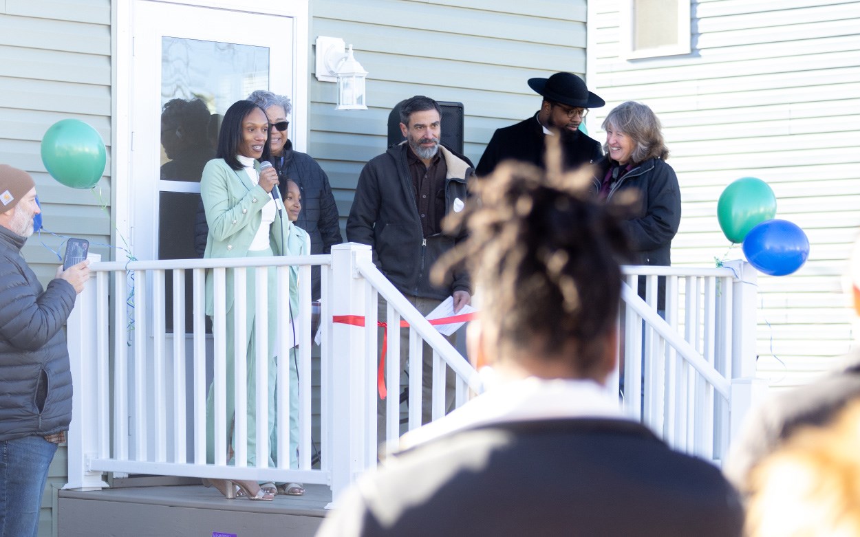 Nahdijah Hunt, using a microphone and standing on the back porch of her new home, thanks supporters who helped her family reach this moment.