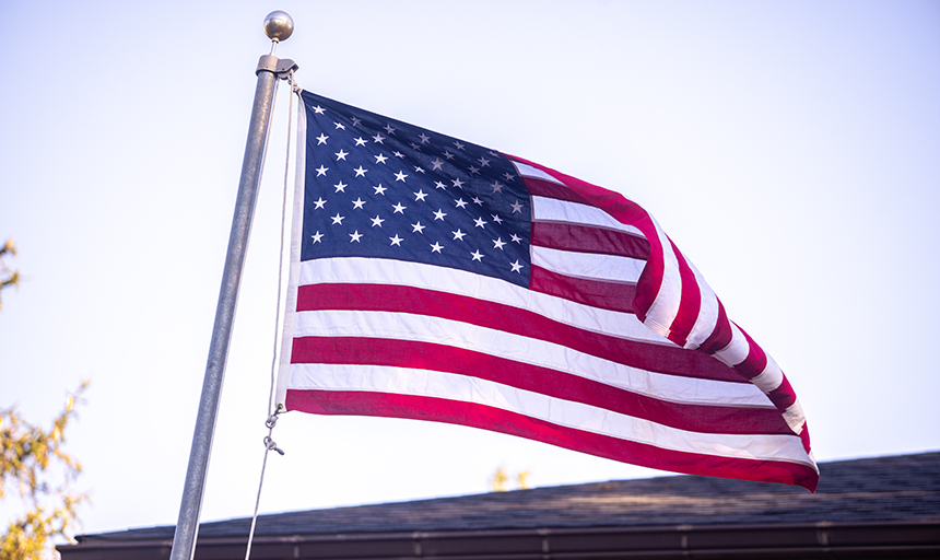 An American flag flying on a flagpole with sky in the background