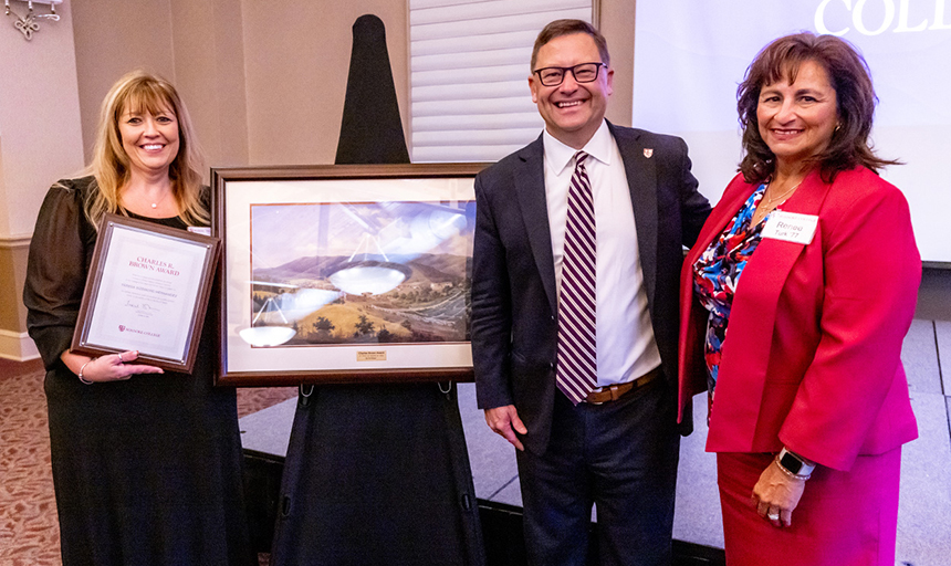 Teresa Sizemore, Mayor Renee Turk and President Frank Shushok Jr. smile for a photo while gathered around a landscape painting presented to Sizemore as part of her award