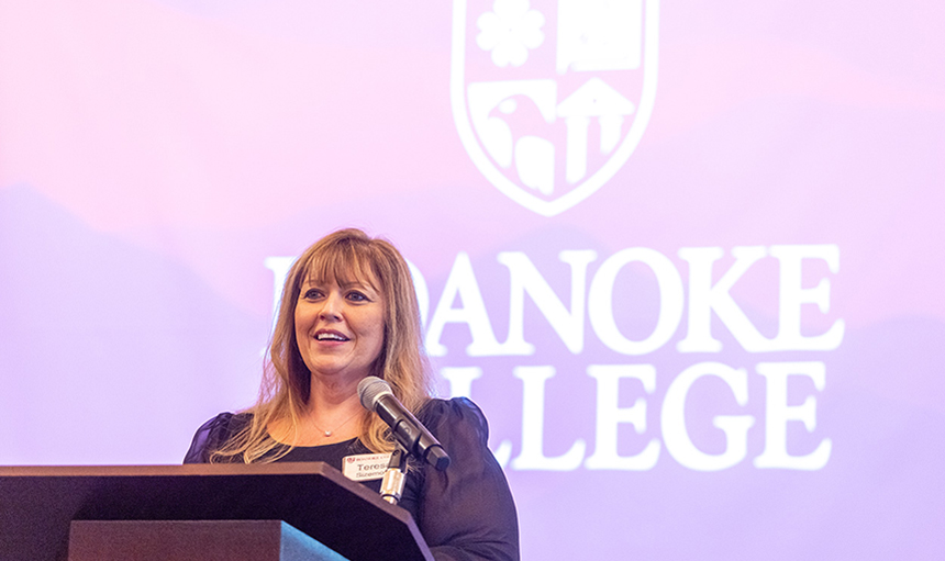 Close-up photo of Teresa Sizemore speaking at a podium with a backdrop of the Roanoke College logo in the background