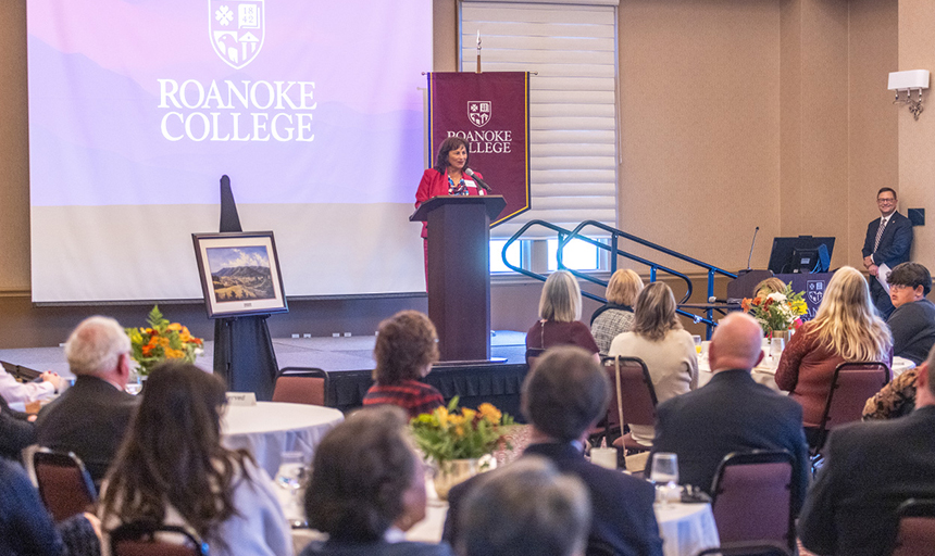 Wide shot of Mayor Turk speaking from the podium before an audience of people seated at tables in Wortmann Ballroom