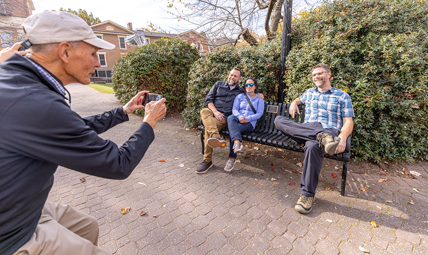 Mac Johnson takes a picture of three people on a bench