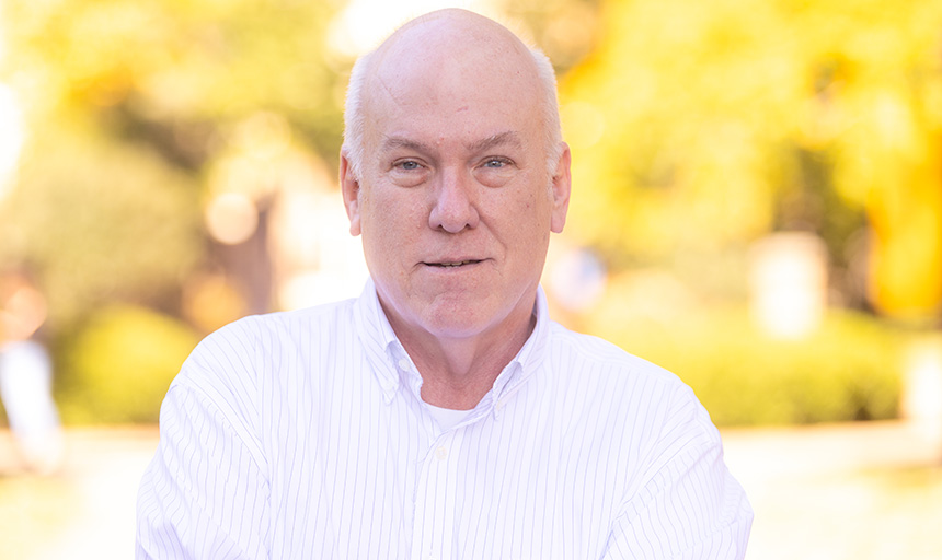 Man in a white shirt with yellow trees in background