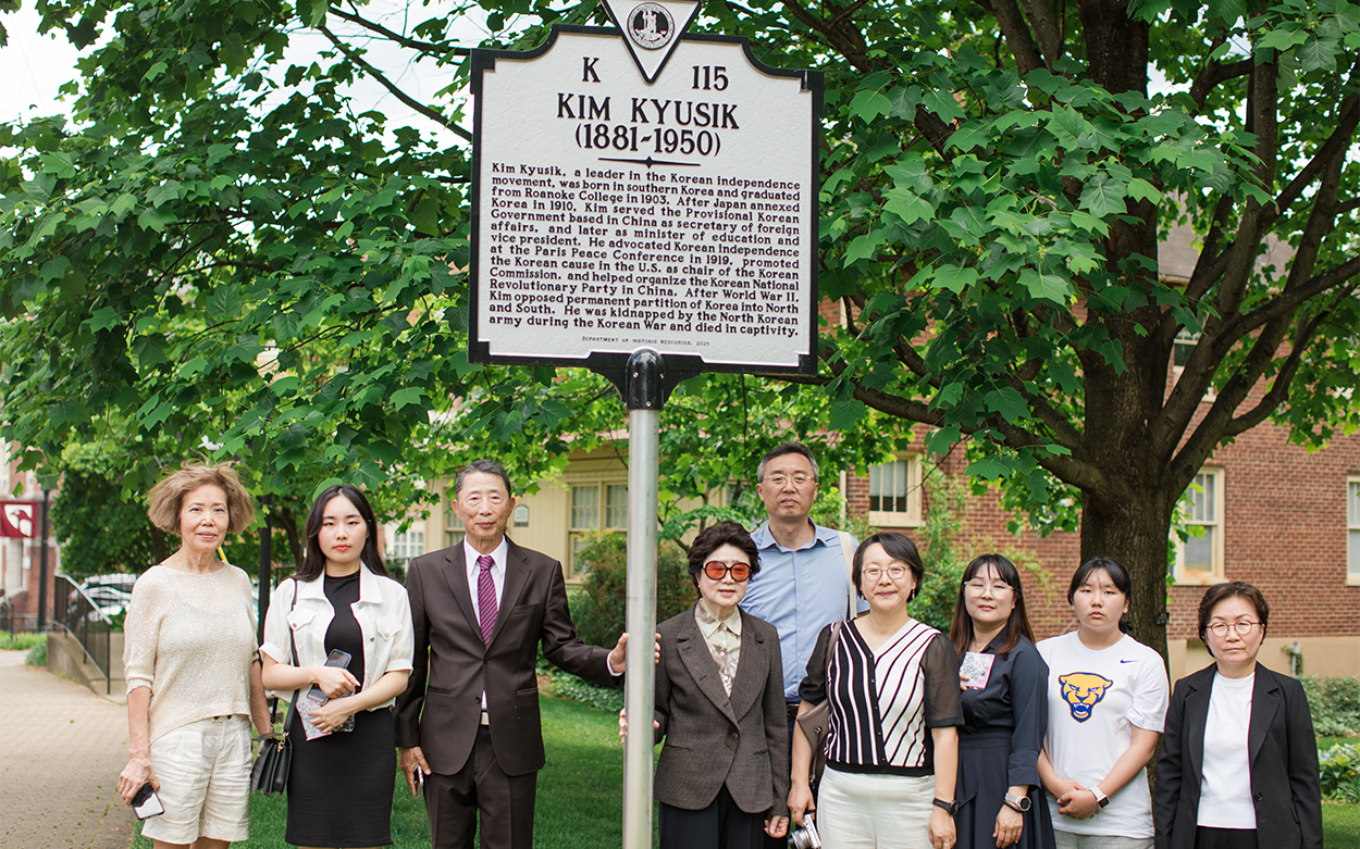 Nine people stand by the historic marker for Kim Kyusik