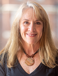 Headshot of a woman with white-blonde hair in a black shirt.