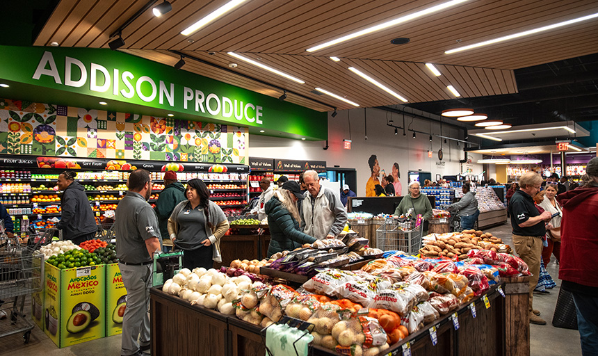 Shoppers push grocery carts through the produce section of a brand-new grocery store