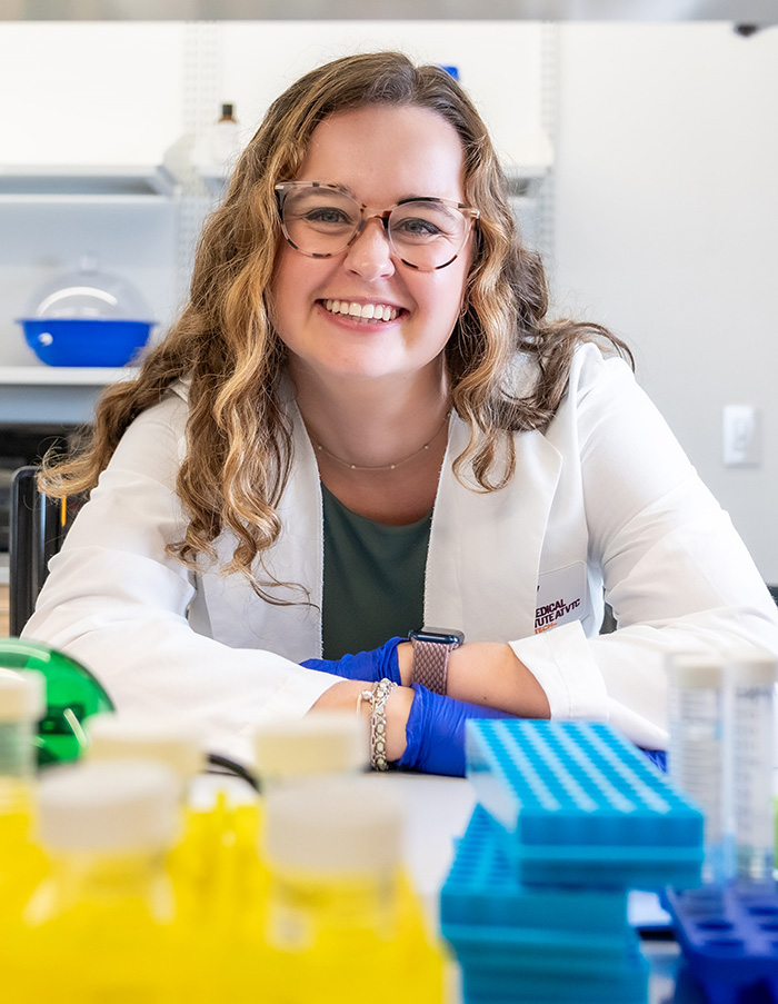 Woman in a white lab coat in a laboratory setting.