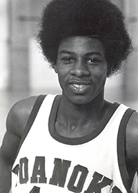 Black-and-white headshot of a man in a white Roanoke College basketball jersey.