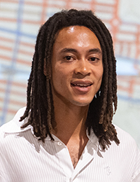 Headshot of a person in a white shirt with braided hair.