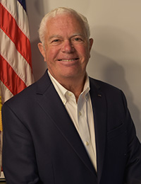 Headshot of an older man with white hair in a dark suit