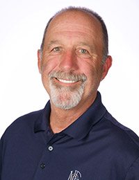 Headshot of a man with salt-and-pepper beard and moustache in a navy blue collared shirt.