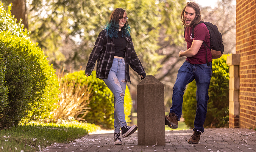 Two students kick the Roanoke College kicking post, a two-foot concrete obelisk, for good luck. 