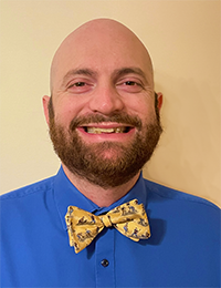 Headshot of a man with a blue shirt and yellow bowtie