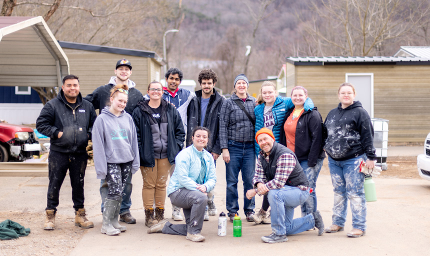 Students, faculty and staff smile for a photo at a work site