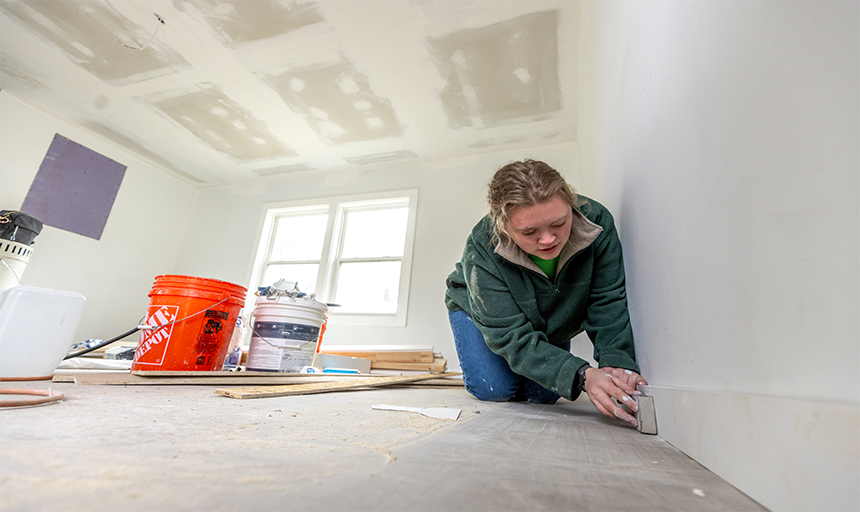 Student sanding the floor boards.