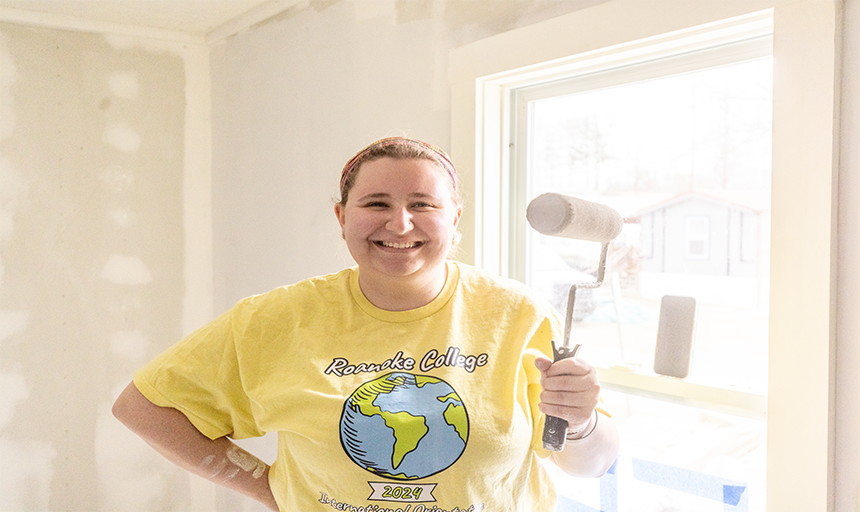 Student smiling with a paint roller.