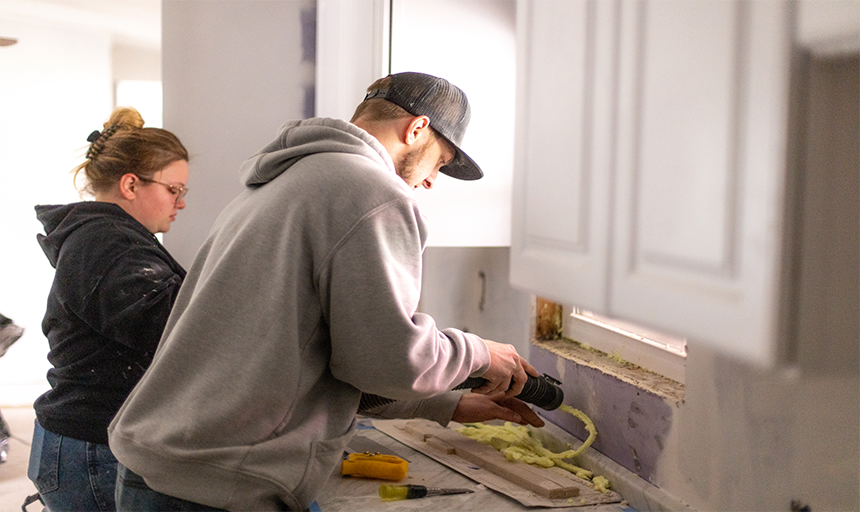 Participants caulking a kitchen window sill.