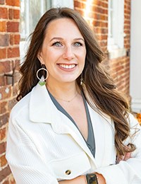 Headshot of a dark-haired woman in a white blazer