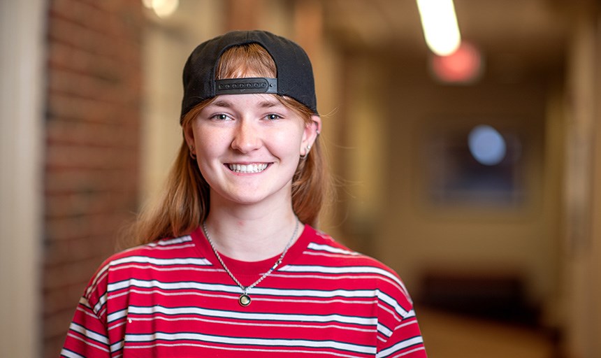 Kaley Hottle, dressed in a striped shirt and her signature baseball cap, smiles for a photo.