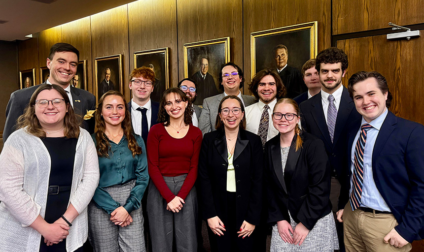 Students smiling for a photo inside a courtroom