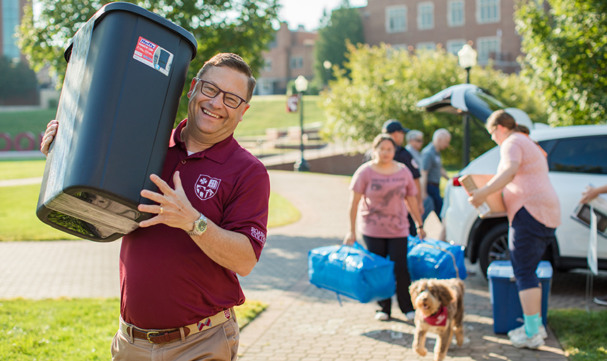 President Shushok helps a student carry her belongings in on move-in day.