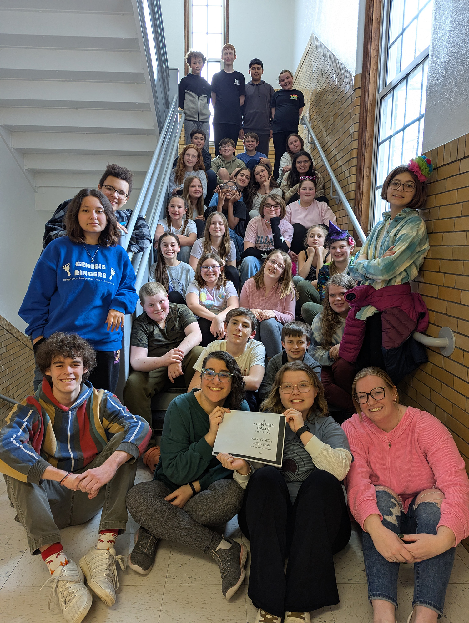 Group of students poses for a photo while sitting together on a flight of stairs