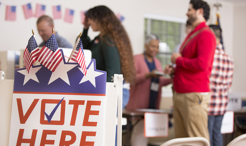 Voters in voting booth while other voters wait in line