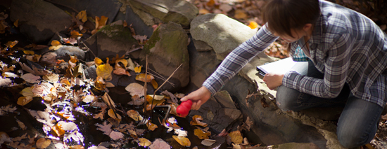 Student conducting research by a creek