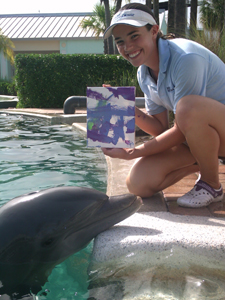 Student working at Miami Seaquarium internship taking photo with a dolphin