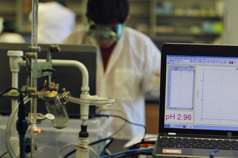 Computer screen in front of Student in chemistry lab wearing goggles