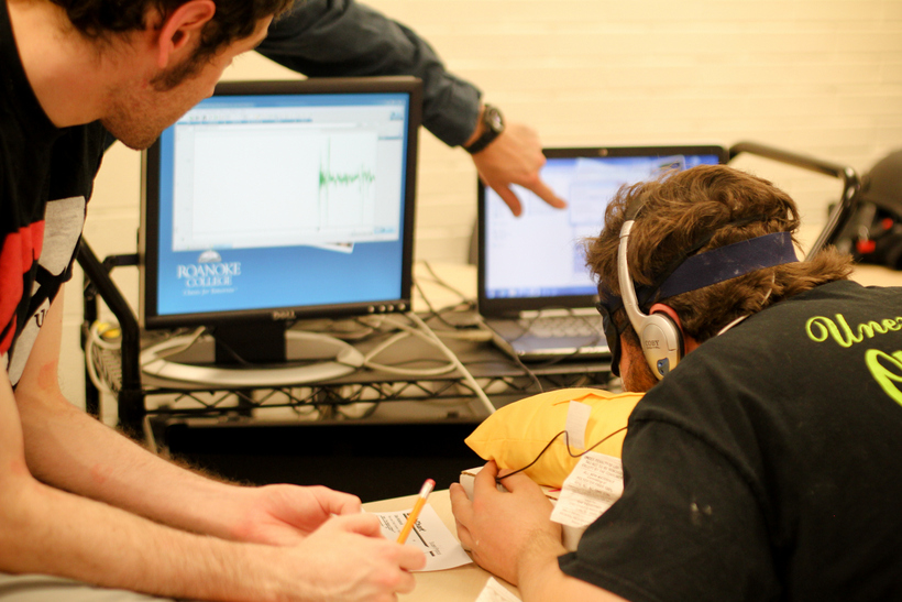A student is hooked up to wires while other students monitor the readings on a computer 